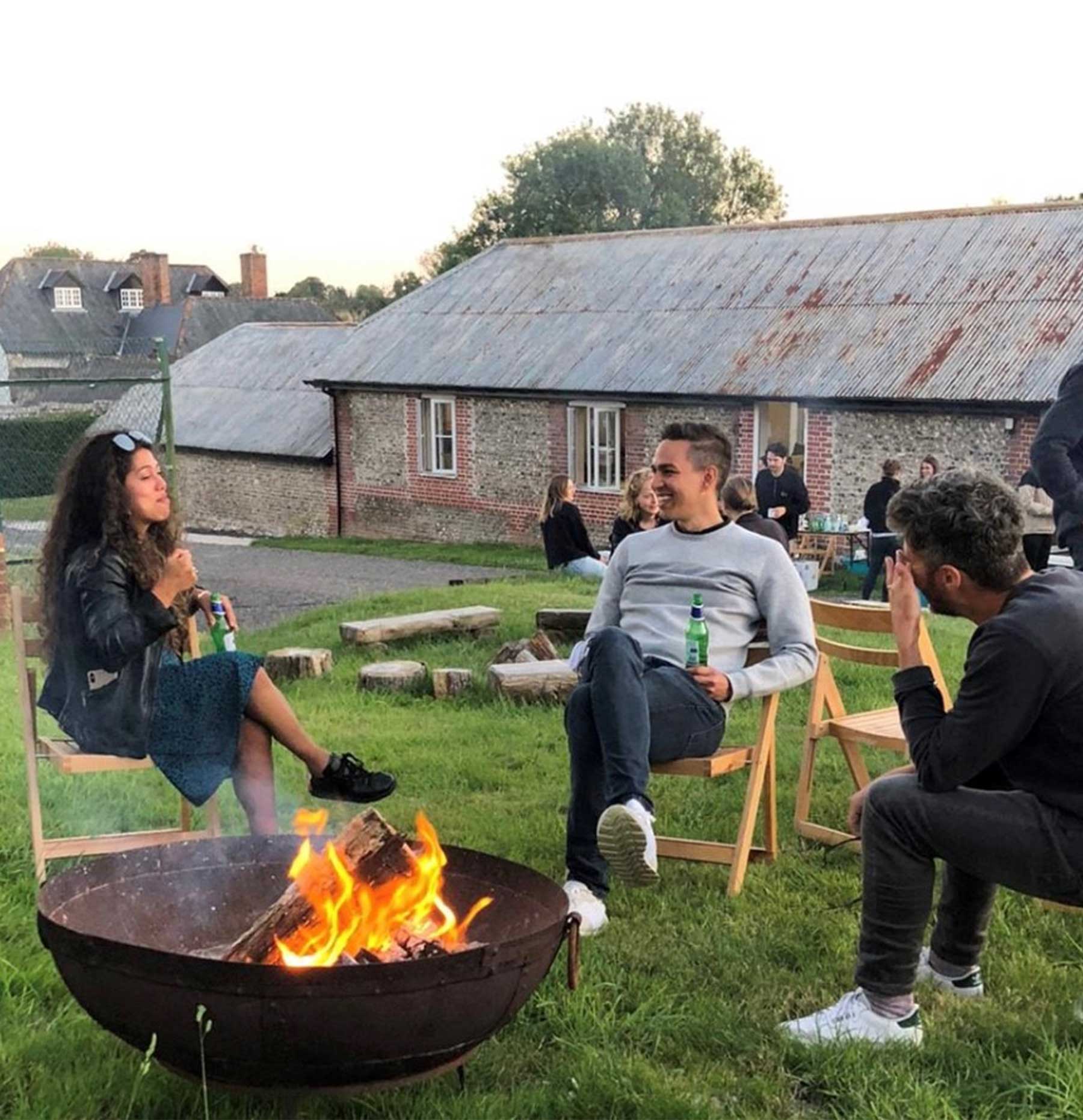 Business retreat guests enjoying a beer around a fire pit at the end of their working day